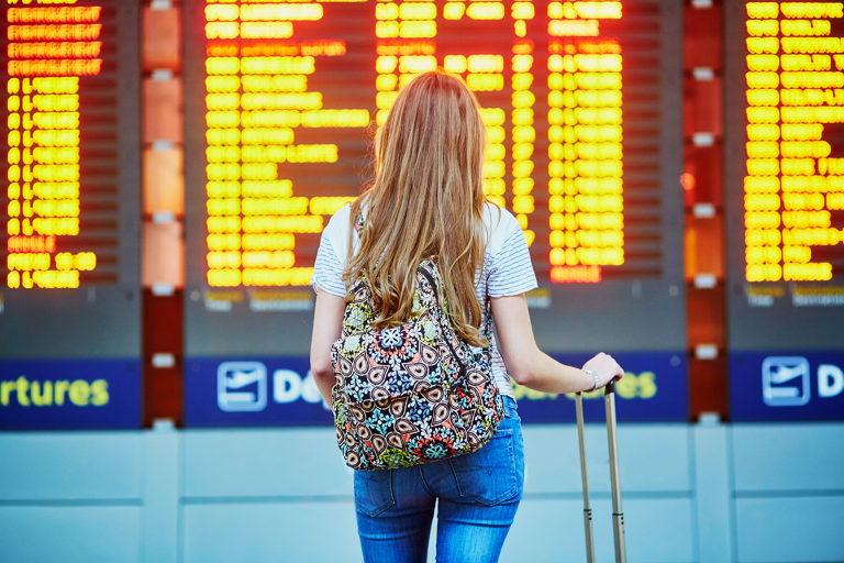 generic-girl-airport-in-front-of-sign