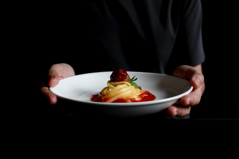generic-hands-holding-spaghetti-dish-dark-background