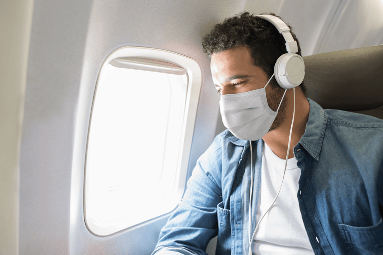 generic-man-airplane-seat-window-view-mouth-mask-headphone